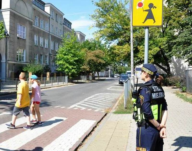 Strażniczka miejska przy przejściu dla pieszych, przez które przechodzą dzieci