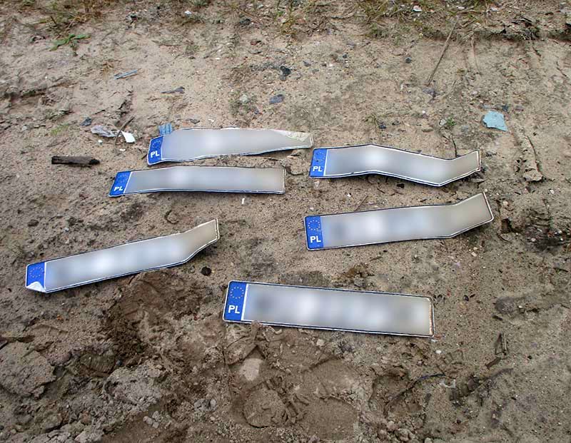 Sześć tablic rejestracyjnych, znalezionych na Białołęce. Leżą na ziemi, w&nbsp;trzech rzędach.