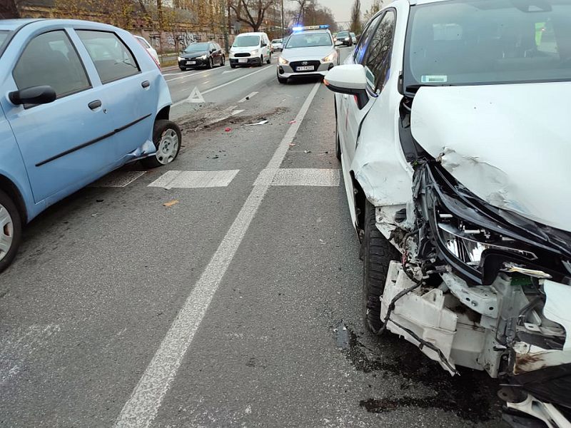 Zdjęcie z&nbsp;interwencji: z&nbsp;prawej strony widać uszkodzony przód białego samochodu. Na lewo stoi błękitny samochód z&nbsp;uszkodzeniami tyłu od strony kierowcy. W&nbsp;tle widoczne samochody, w&nbsp;tym zabezpieczający miejsce zdarzenia radiowóz straży miejskiej.