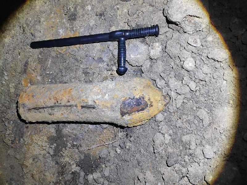 Zdjęcie z&nbsp;interwencji: leżący na ziemi zardzewiały pocisk artyleryjski. Obok, dla ukazania skali, leży pałka strażnika dorównująca wielkością niewybuchowi.