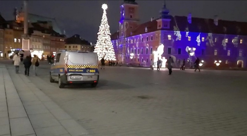 Zdjęcie ilustracyjne: radiowóz straży miejskiej na tle świątecznej iluminacji Zamku Królewskiego i choinki.