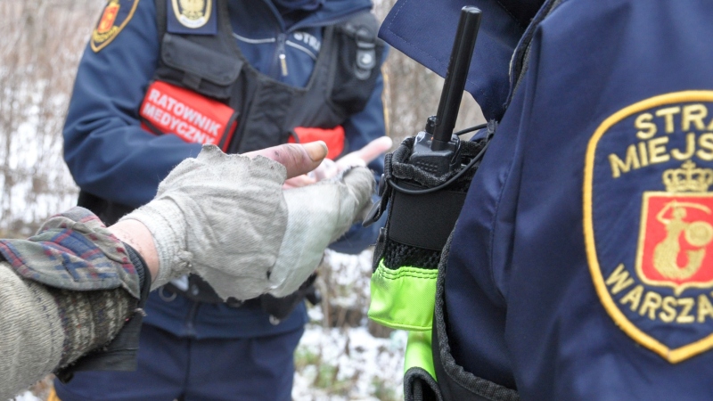 Strażnicy miejscy wydający gorący posiłek bezdomnemu
