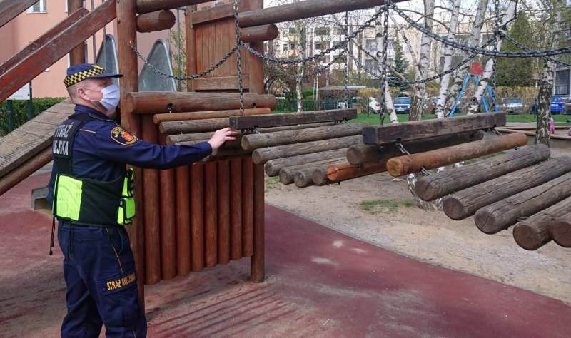 Strażnik miejski przy uszkodzonym urządzeniu na placu zabaw