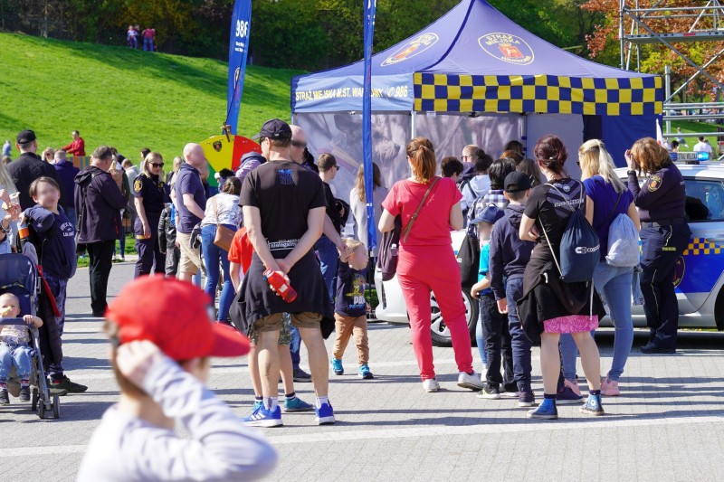 Grupa ludzi na pikniku plenerowym, przy namiocie Straży Miejskiej.