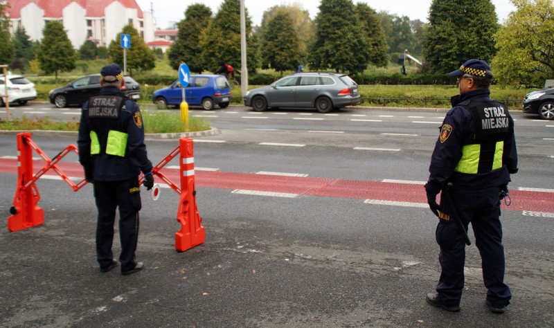 Strażnicy miejscy zabezpieczający zamknięty odcinek ulicy.